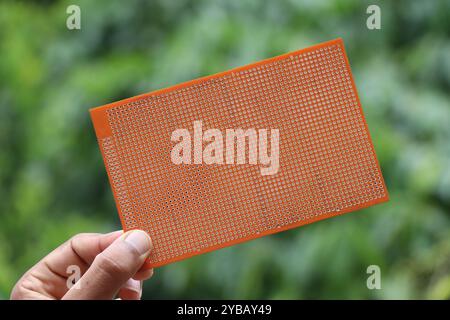Universal double sided printed circuit board or PCB for prototyping electronics project held in the hand Stock Photo