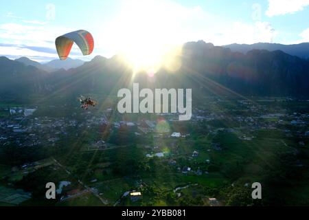 Paramotor carry tourist flying over city of Vang Vieng, Laos Stock Photo