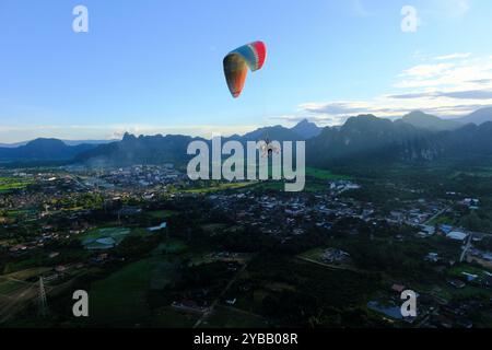 Paramotor carry tourist flying over city of Vang Vieng, Laos Stock Photo