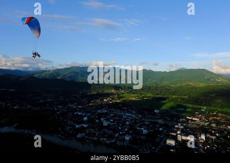 Paramotor carry tourist flying over city of Vang Vieng, Laos Stock Photo