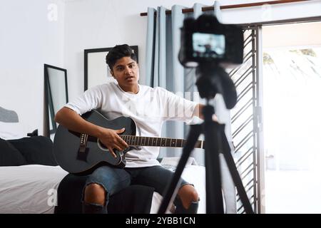 Recording, influencer and man with guitar in home for live streaming, vlog and social media. Content creator, camera and person with musical Stock Photo