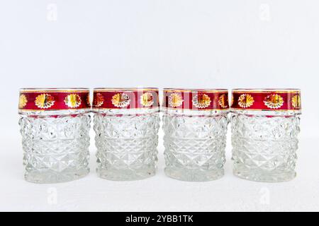 A row of vintage crystal glass cups with decorated rims, isolated on a white background. Stock Photo