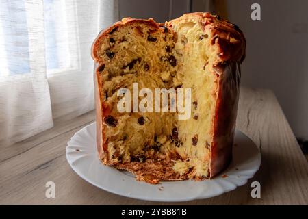 An Italian Panettone, Christmas cake on a sideboard, with a slice cut showing fruit and texture inside. Stock Photo