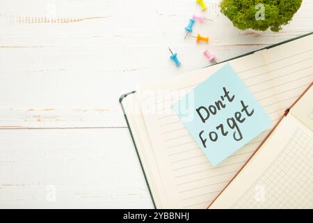 Open notepad and sticky notes with word don't forget on white background. Top view Stock Photo