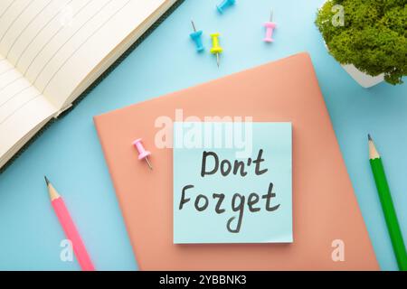 Open notepad and sticky notes with word don't forget on blue background. Top view Stock Photo