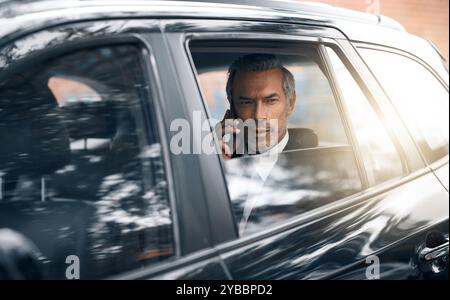Businessman, passenger and talking in car window with phone call, communication and connection. Male person, entrepreneur and serious on vehicle or Stock Photo