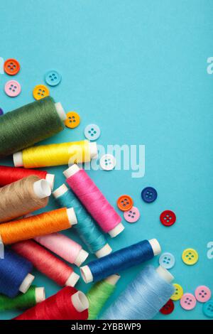 Colorful buttons with colorful thread on blue background. Top view Stock Photo