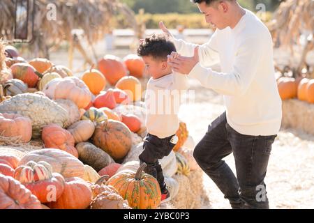 Father and son climbing through hay and pumpkins Stock Photo