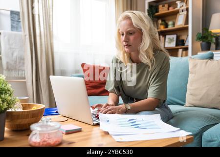 Serious concentrated pensive woman using laptop computer work from home office, communicating online, distantly working or studying for exam. Young fr Stock Photo