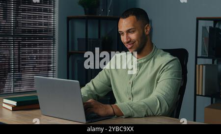 Smiling african american business man businessman guy male entrepreneur freelancer typing on laptop computer working remote on internet in home office Stock Photo