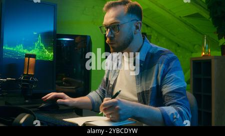 Focused serious Caucasian man freelancer male modern guy working writing results programmer crypto analyst typing keyboard computer pc concentration e Stock Photo