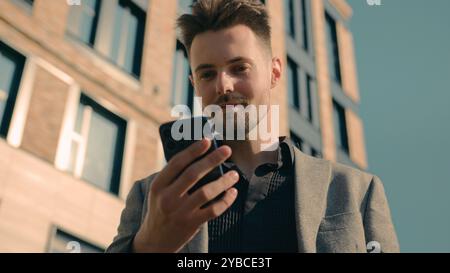 Happy successful caucasian man businessman male guy online winner checking email reading good news using smartphone in city outdoors near office Stock Photo