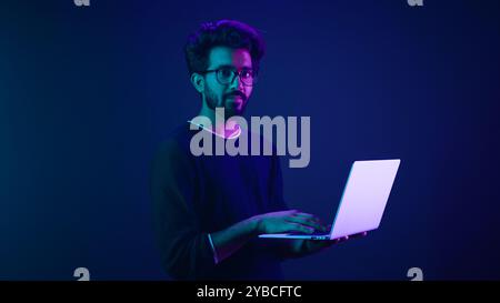 Arabian Indian man guy male programmer coder employer freelancer working using internet computer developer businessman business guy gamer hold laptop Stock Photo