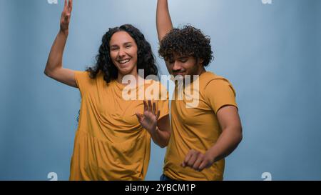Multiracial diverse couple Indian Arabian man guy Hispanic Caucasian woman girl dancing together to music having fun enjoying funny active moving Stock Photo
