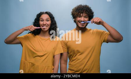 Multiracial couple Hispanic woman girl and Indian man Arabian guy holding tooth brush pretend brushing teeth dental care using toothbrushes oral Stock Photo