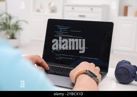Programmer working with laptop at white desk in office, closeup Stock Photo