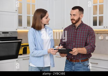 Woman and repairman signing documents near oven in kitchen Stock Photo