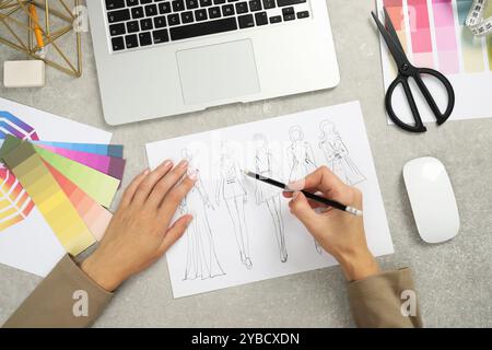 Fashion designer drawing sketch of stylish clothes at gray textured table, top view Stock Photo