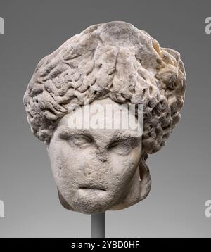 Head of Apollo (Lykeios-Cyrene type), 2nd century A.D.  Additional Info: Despite the severely abraded facial features on this over-life-size head, the subject can be identified as a representation of Apollo. Three details secure this identification: the full hairstyle with an upturned central braid, the downwards tilt of the head, and the still-visible remains of a hand placed casually across the top of the head. These are the standard features employed in the widely-used sculptural type known as the Apollo Lykeios, and this head is especially close to a subtype known as Apollo of Cyrene. In t Stock Photo