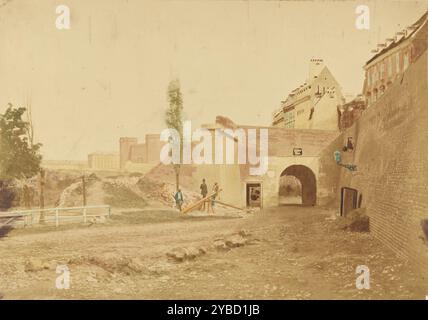 Demolition of Fisher Gate, about 1859. Three men standing at the base of a small hill beside stacked wooden beams. A partial brick wall is standing behind the men. There is an arched passageway leading through the wall with a sign labeling it &quot;Fischer Thor.&quot; Bricks from the wall are piled on the small hillside. Stock Photo