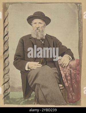 Alexander D. Grant, Jr., about 1860s. Portrait of a seated older man, resting one arm on a small table covered in a floral pattern tablecloth. The man is wearing a wide brimmed hat and has a curly beard and mustache. He has one hand resting on his lap near his vest pocket. Stock Photo