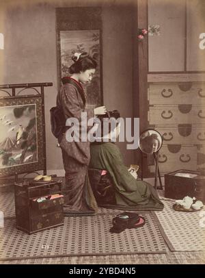 Hair Dressing, 1870s-1890s. A woman standing behind another woman, arranging her hair. Stock Photo