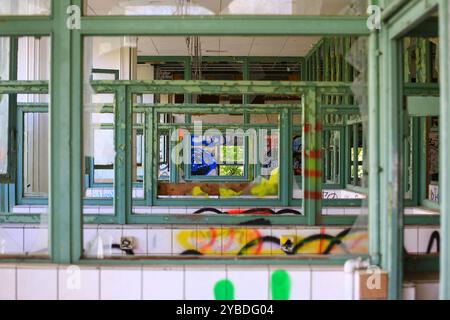 Green frames with peeling paint in abandoned building featuring graffiti and broken glass. Stock Photo