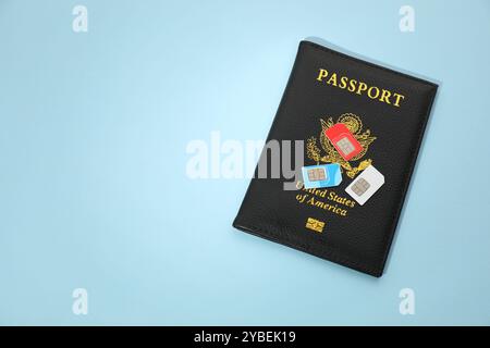 Modern SIM cards and passport on light blue background, top view. Space for text Stock Photo