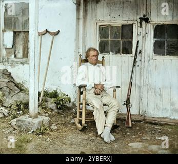 John L. Burns, the 'old hero of Gettysburg,' age 69, with his rifle and a pair of crutches propped up behind him in 15th July 1863, Gettysburg, Pennsylvania. Photographed by Timothy H. O'Sullivan. A combination of two stereographs from wet collodion negatives. Stock Photo