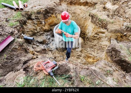 Worker connects rotary hammer to power supply using an extension cord. Stock Photo