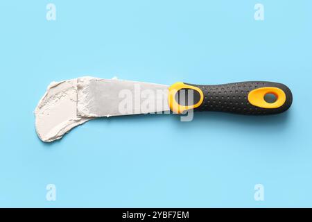 Knife with putty on blue background Stock Photo
