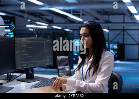 Data center specialist developing emergency procedures to ensure business continuity in case of disaster or system failure. Woman in server farm ensuring compliance with industry regulations Stock Photo