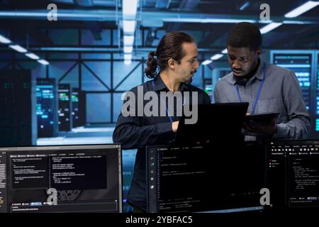 Teamworking admins in server farm checking recovery plan, monitoring energy consumption. Coworkers in data center workspace making sure sensors are functioning optimally, doing routine disk checks Stock Photo