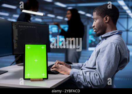 Supervisor using chroma key tablet to reconfigure server room, optimizing it for data processing requirements. Manager using isolated screen device, ensuring data center tech operates efficiently Stock Photo