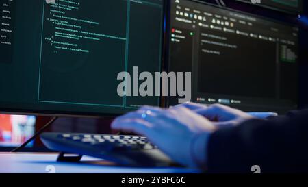 Cybercriminal illegally breaching security systems while hiding in secret HQ, close up shot. Scammer breaking down security systems firewalls using rogue scripts to steal sensitive data, camera B Stock Photo