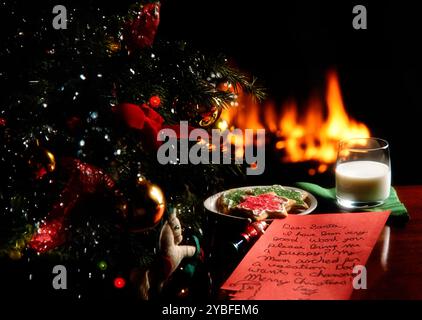 A cozy Christmas scene with milk, cookies, and a letter to Santa beside a beautifully decorated tree and a warm fireplace Stock Photo