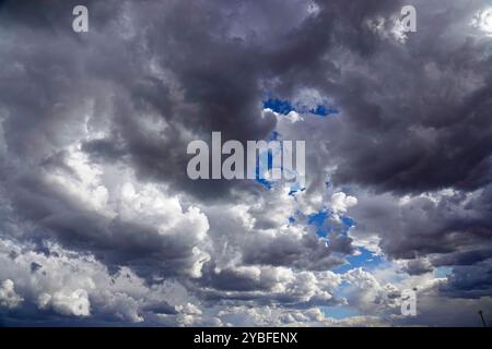 Gathering storm clouds loom overhead, filled with varying shades of gray and white, revealing patches of blue sky during the afternoon hours, suggesti Stock Photo