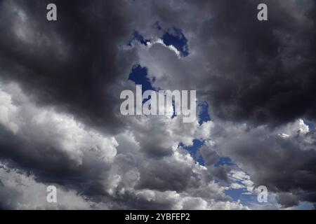 Gathering storm clouds loom overhead, filled with varying shades of gray and white, revealing patches of blue sky during the afternoon hours, suggesti Stock Photo
