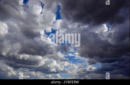 Gathering storm clouds loom overhead, filled with varying shades of gray and white, revealing patches of blue sky during the afternoon hours, suggesti Stock Photo