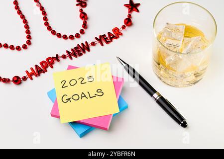 Pile of writing squares ready for 2025 goals with pen drink red beads Stock Photo