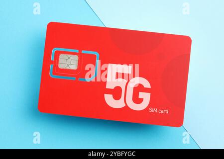 Red 5G SIM card on light blue background, top view Stock Photo