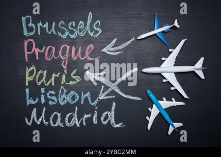 Traveling concept. Toy plane over chalkboard with cities written on it Stock Photo