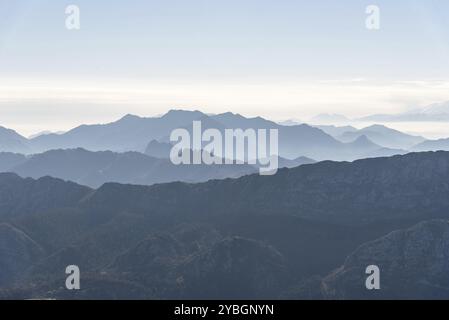 Scenic view of silhouettes of mountains in the morning mist with snowcapped mountains on background. Picos de Europa, Asturias, Spain, Europe Stock Photo