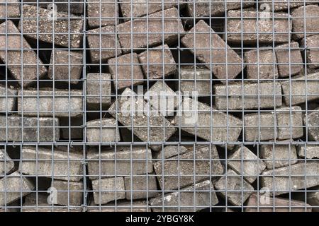Stone wall built of concrete bricks and metal mesh Stock Photo