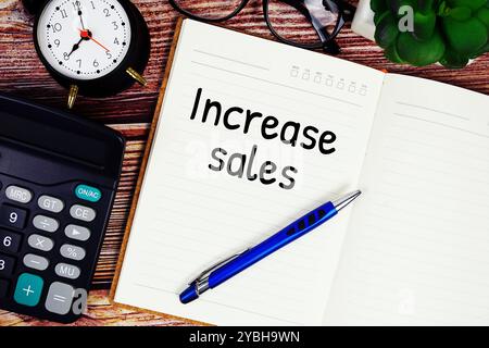 Increase sales text on note page with alarm clock and calculator top view on wooden background Stock Photo