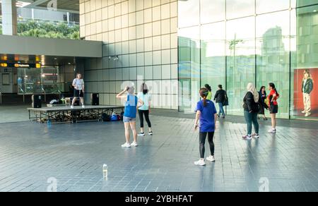 Group of women doing fitness with an instructor in the public space outside Suntec city shopping mall Marina Centre, Downtown Core in Singapore, Stock Photo