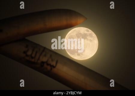 The moon rises behind the crossed swords at the Grand Festivities Square in Baghdad, Iraq - 19 October 2024 Stock Photo
