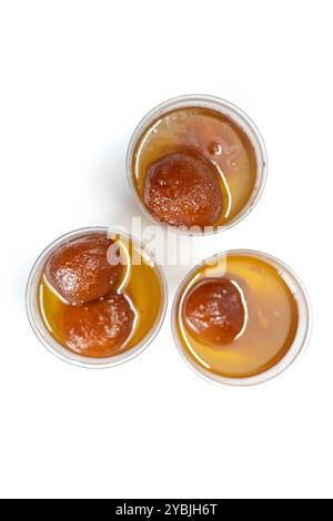 Top view of delicious gulab jamun sweets floating in sugar syrup in small three cups on white background. selective focus Stock Photo