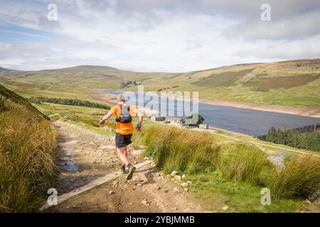 Yorkshire Dales, UK - September 14, 2024. Man trail running downhill toward Scar House Reservoir, Nidderdale, North Yorkshire, UK Stock Photo