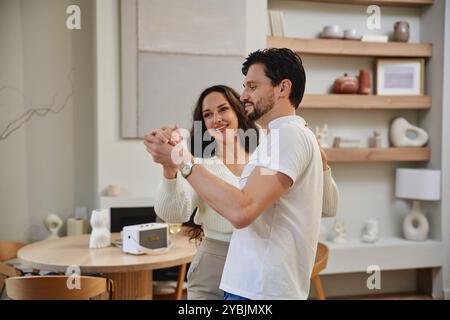 Couple enjoys a dance together in a bright, modern living room setting Stock Photo